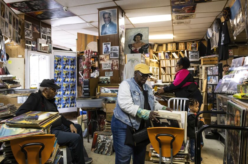 Marie Henderson, owner of Out of the Past Records, sorts albums as customers mingle and family members work at her store in West Garfield Park.