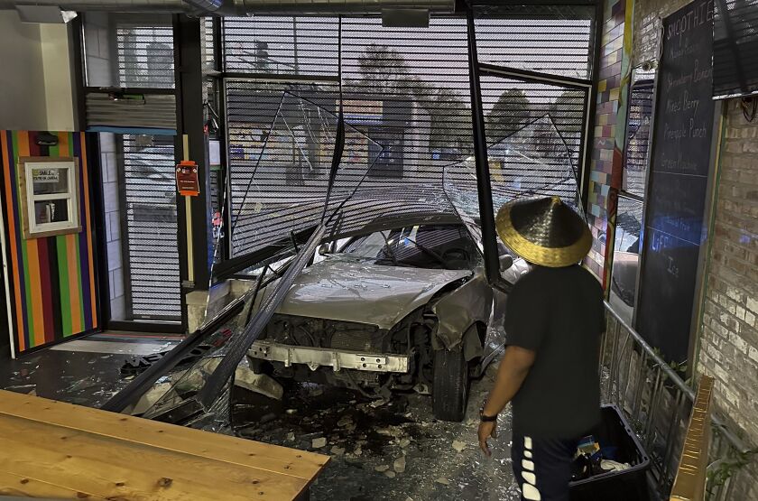 A man and a woman, Joe Black and his wife, Tonya, look out at broken glass and a car that has broken through the front window of their restaurant.