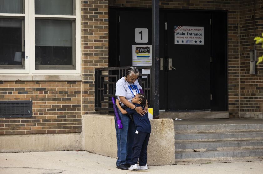 Cornell Moses Jr., 6, hugs a school employee while waiting for his mother at Genevieve Melody Public School in West Garfield Park.