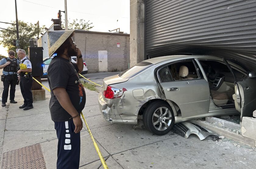 Owner Joe Black surveys the damage after a car has crashed into the front window of their restaurant. The car is dented and the windows of the car are broken. 