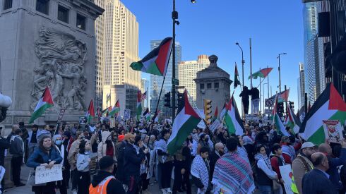 Thousands of pro-Palestinian protestors march the streets of downtown Chicago, holding Palestinian flags and signs.